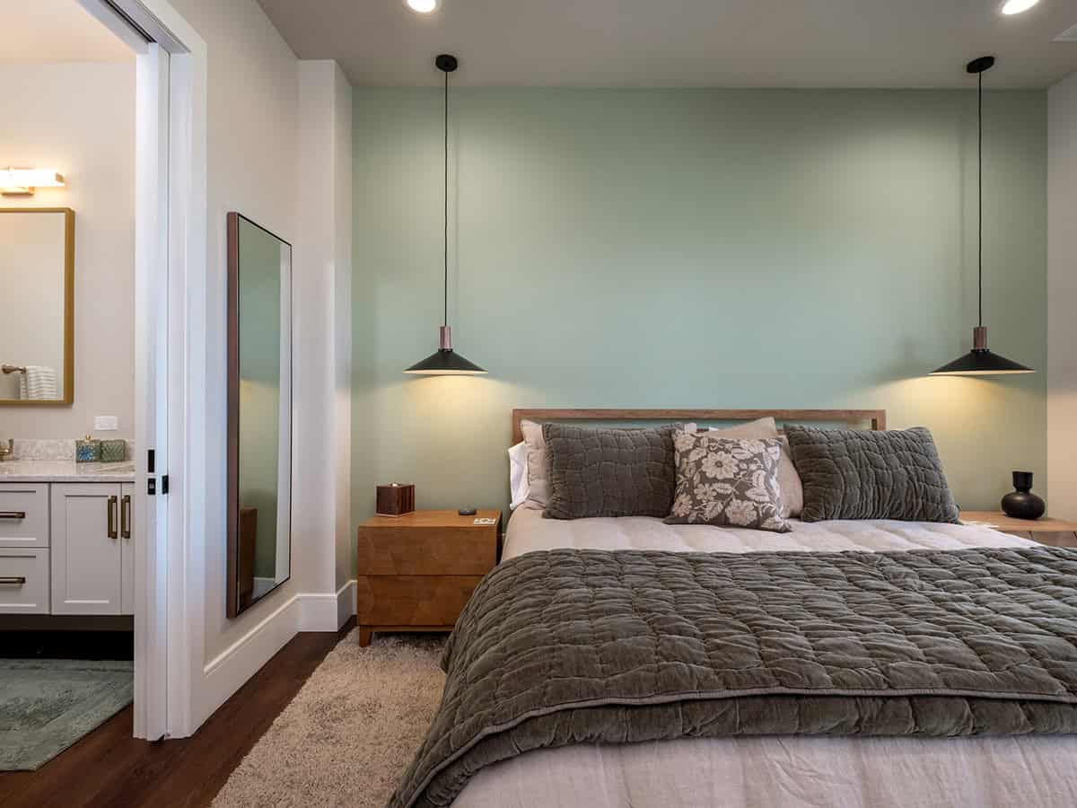 Bedroom with sage wall, pendant lights, and ensuite view