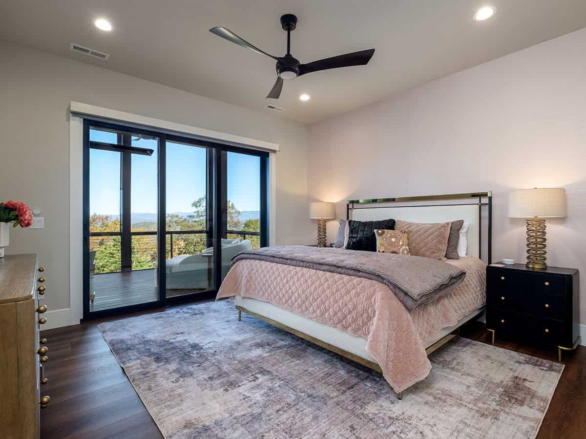 Bedroom with pink bedding, ceiling fan, and deck access