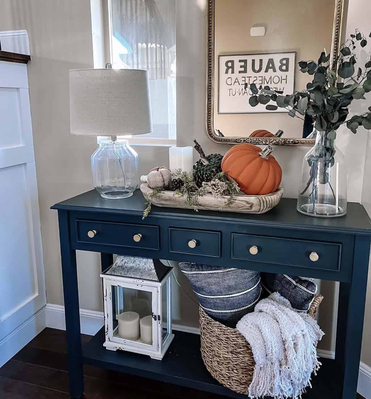 Navy console table with wood tray of pumpkins, pinecones, and eucalyptus in glass vase