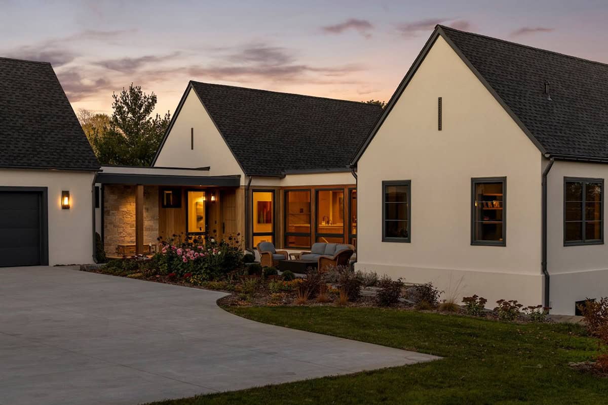 Modern gabled home exterior glowing at dusk with curved driveway