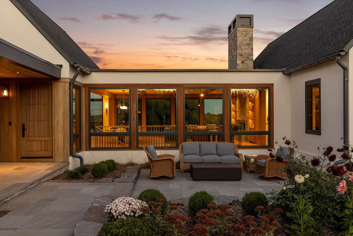 Covered patio with wicker seating facing stone chimney at sunset
