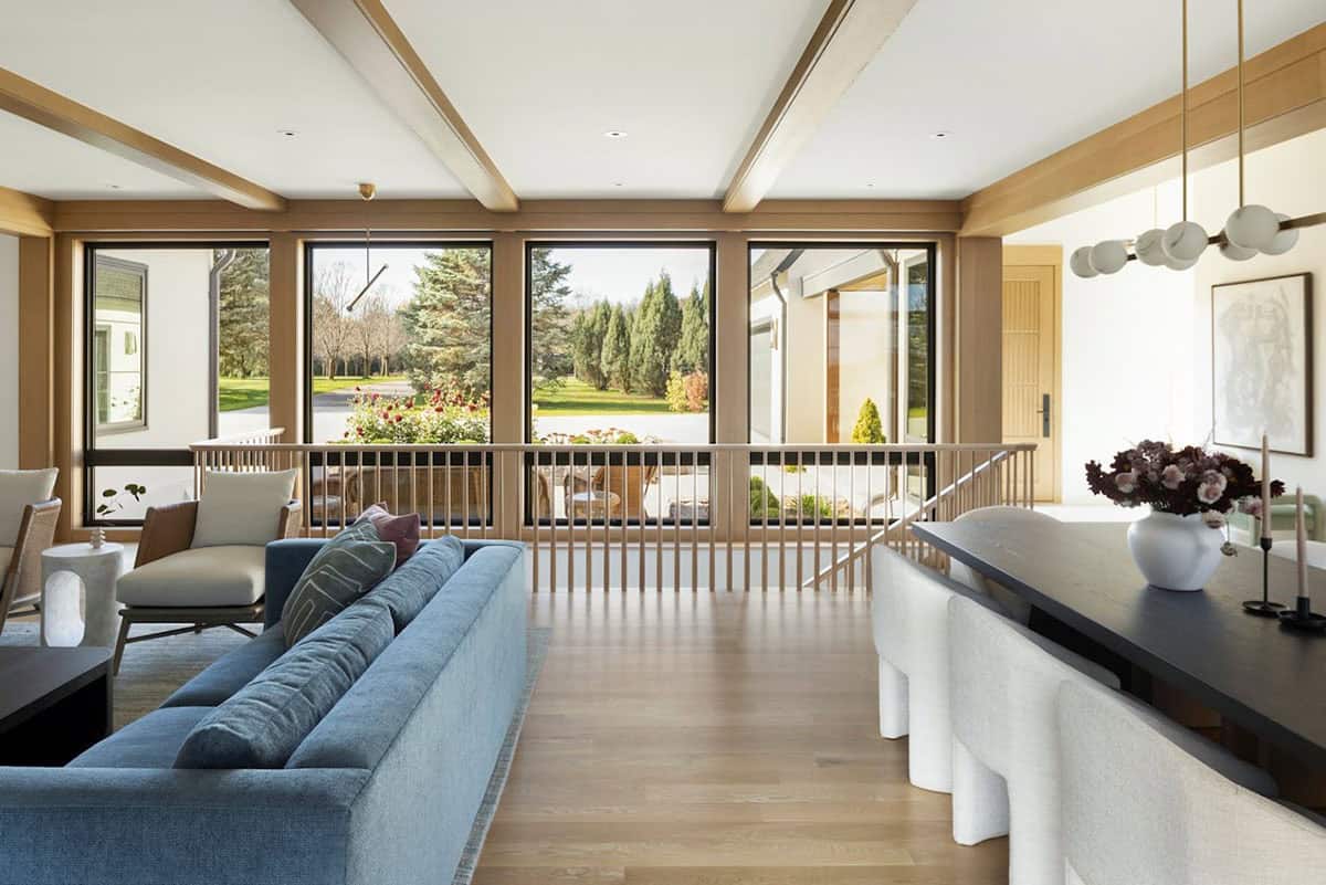 Open loft landing overlooking sunroom with wood beams and railing