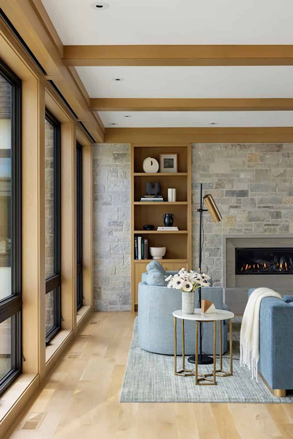 Reading nook with blue chairs, stone wall, and gas fireplace