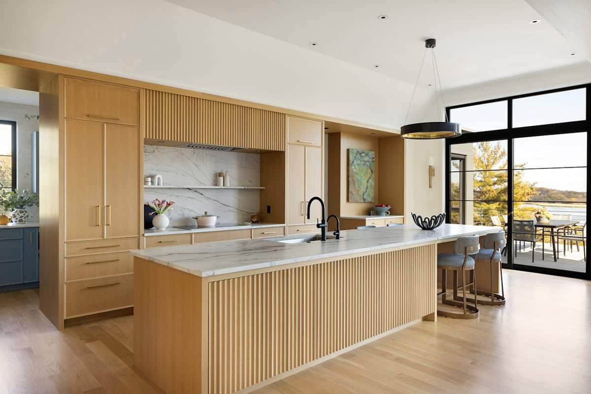 Fluted wood kitchen island with marble countertop and blue stools