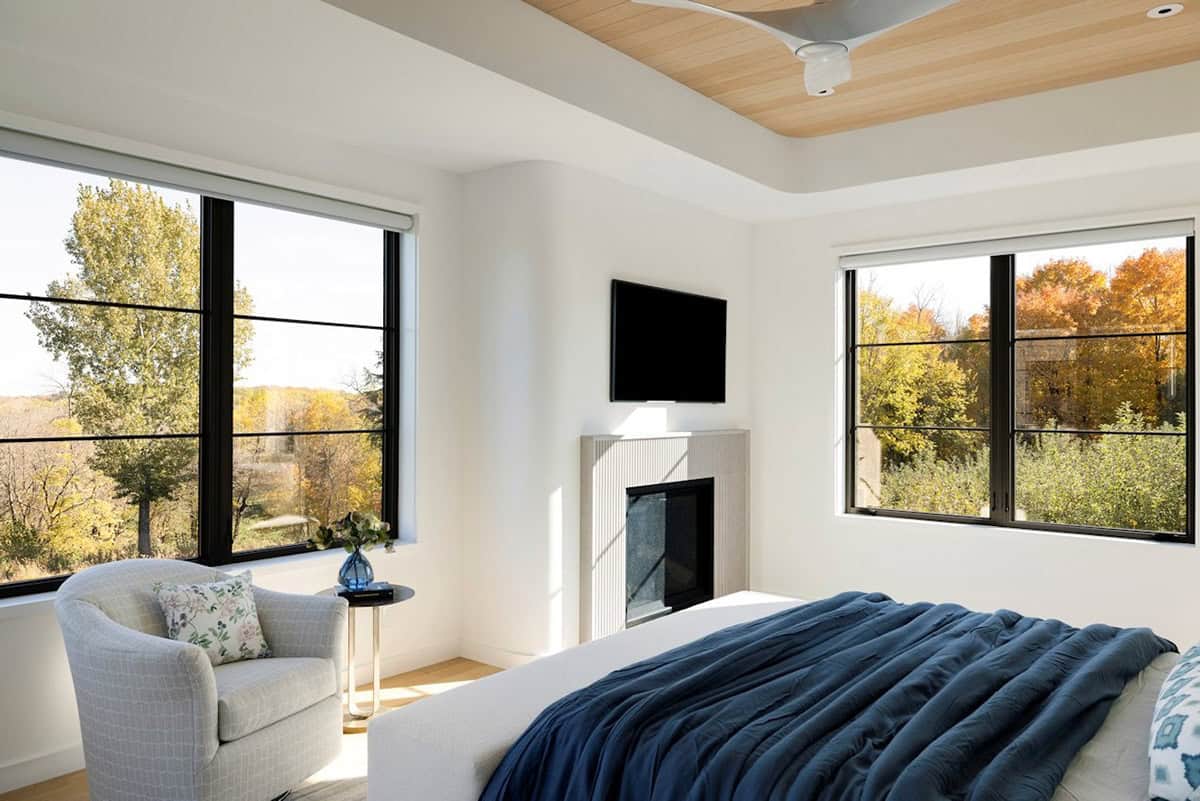Primary bedroom with tray ceiling, fireplace, and large black windows