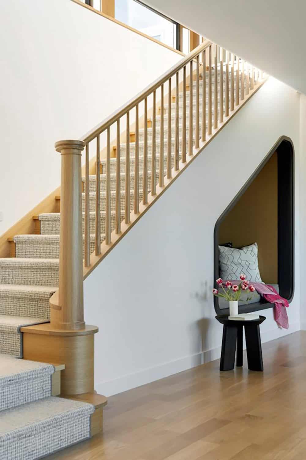 Staircase with wood railing and built-in reading nook below