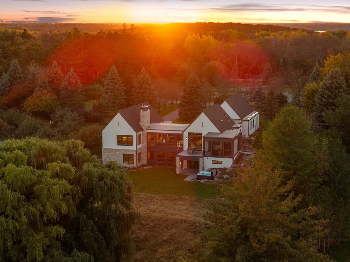 Aerial view of home surrounded by autumn trees at sunset
