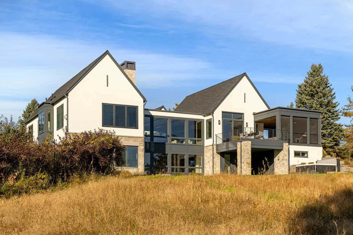 Rear exterior of white stucco home with stone base and deck