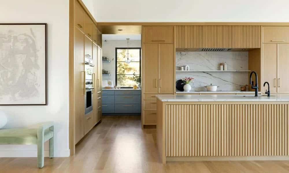 Fluted wood cabinetry with marble backsplash and open shelving