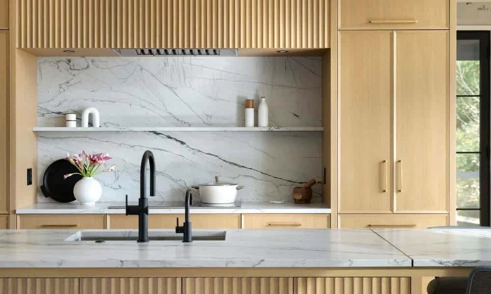 Marble backsplash with open shelving and matte black kitchen faucet
