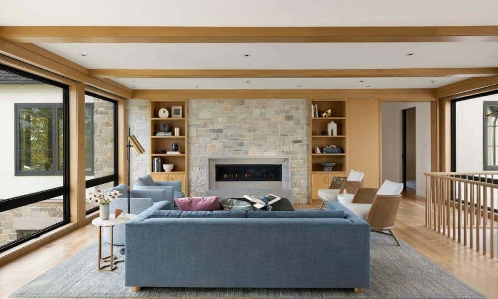 Living room with stone fireplace, blue sofa, and built-in shelving