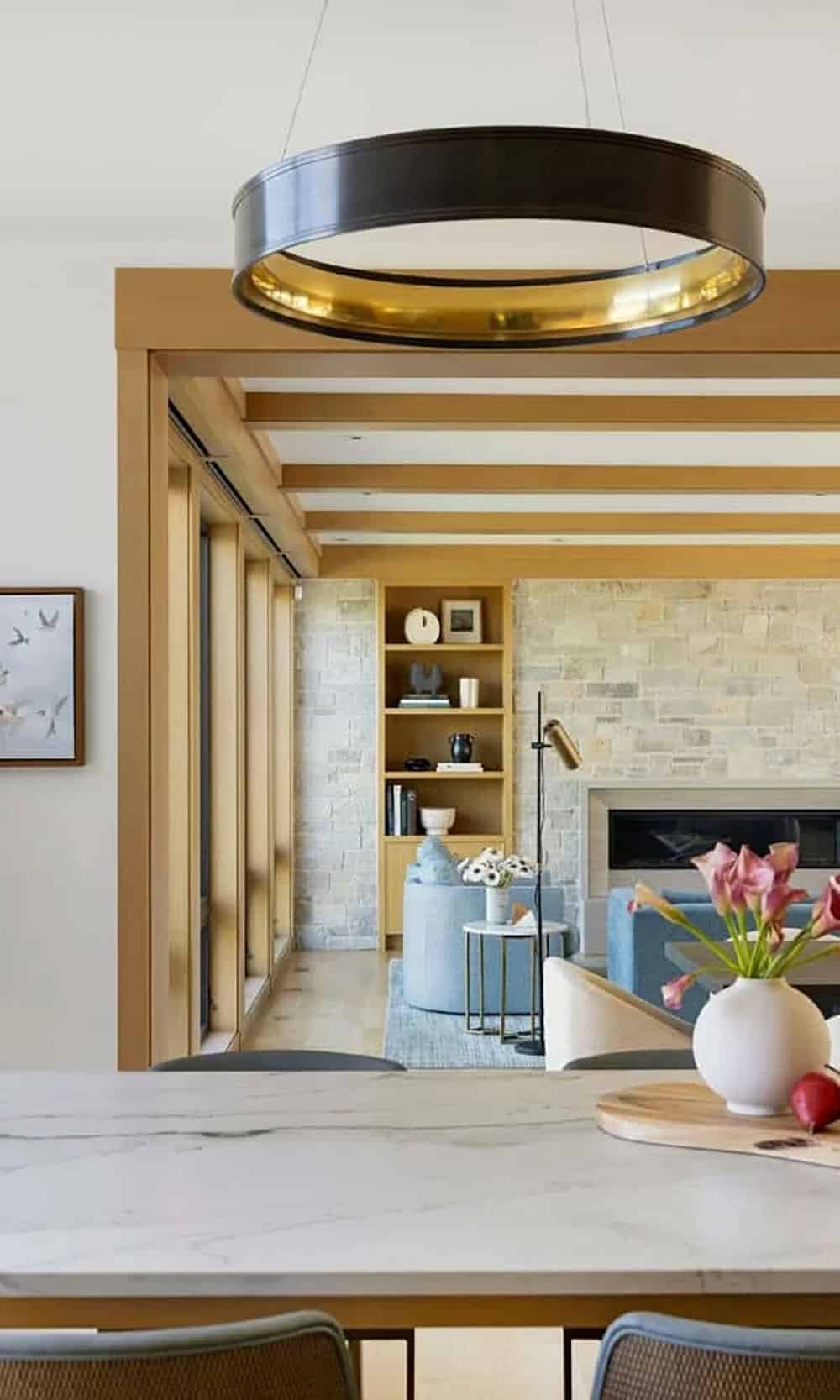 Dining table view into living room with stone fireplace beyond