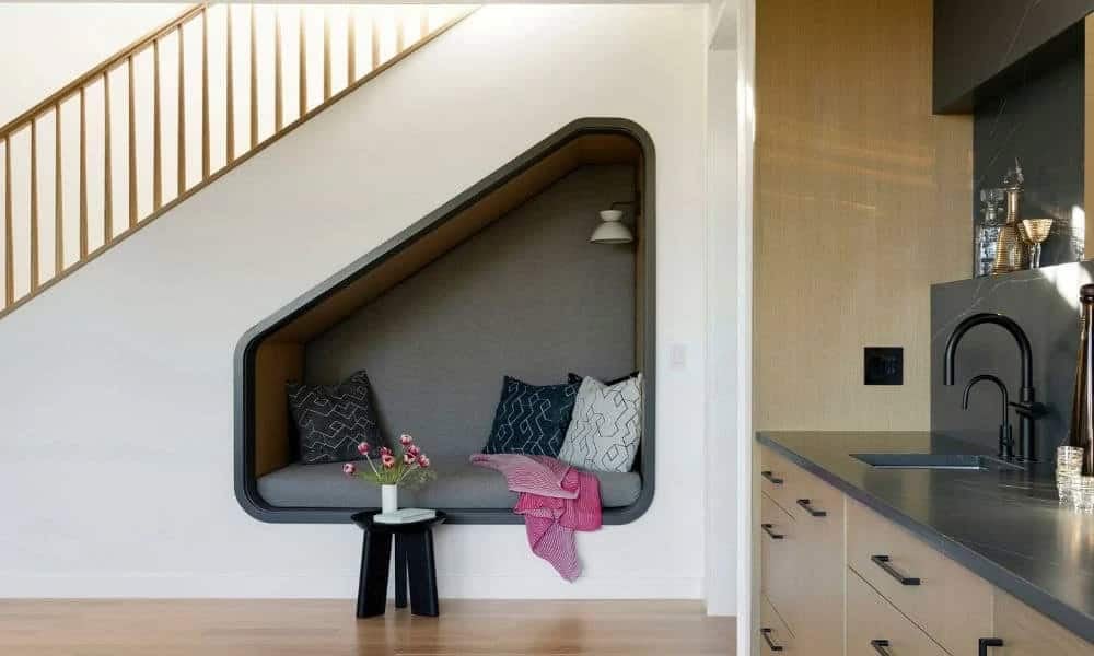 Built-in window seat nook beside wood staircase and bar cabinetry