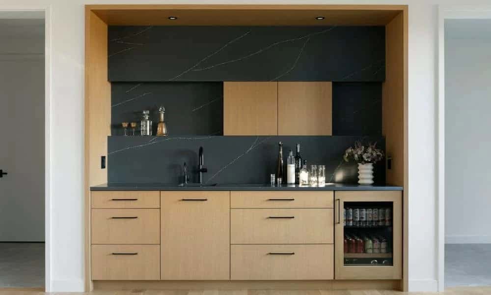 Wet bar with dark stone backsplash and glass-front beverage fridge