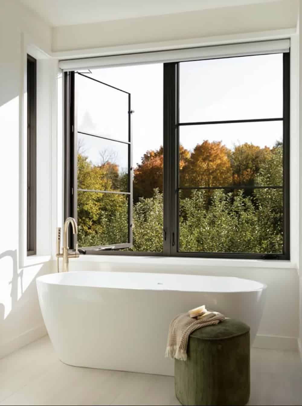 Freestanding tub with brass faucet facing black-framed window