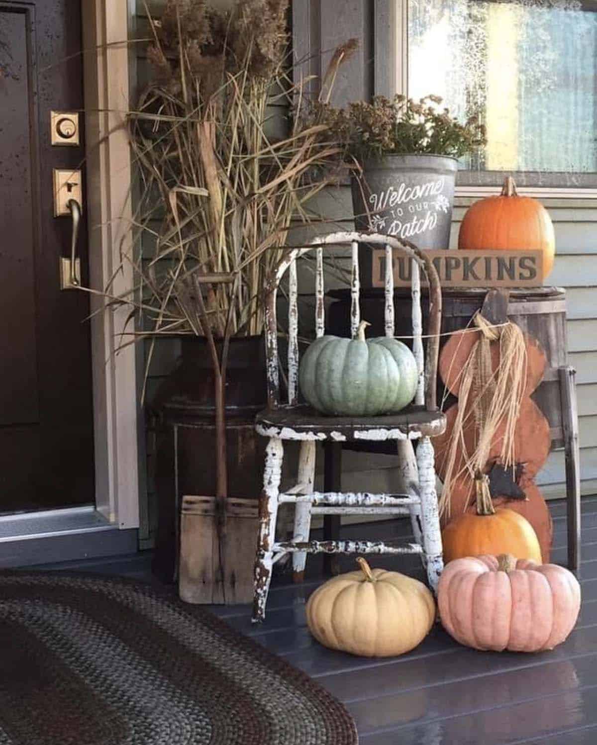 Vintage chair with pumpkins, metal can, and dried grasses beside front door