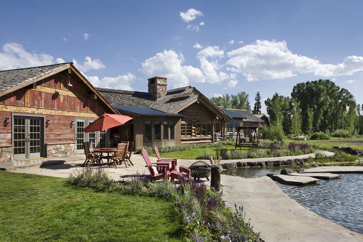 Stone patio with red barn siding beside a private pond