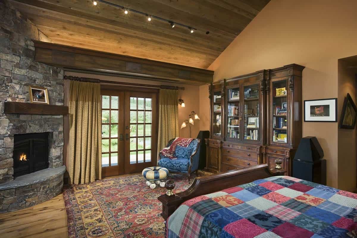 Bedroom with stone fireplace and antique bookcase wall