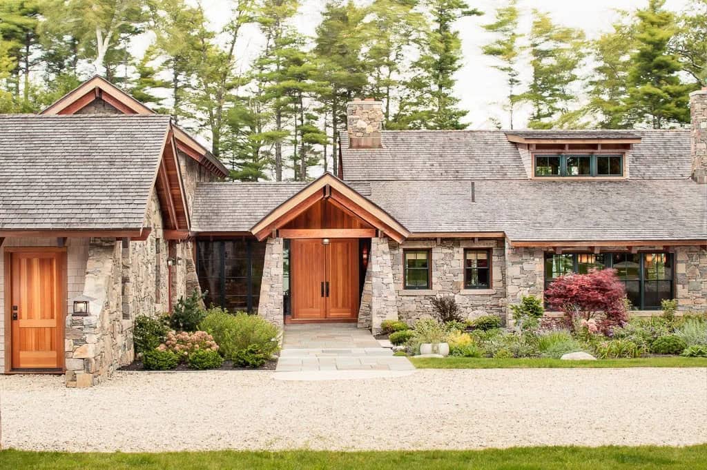 Double wood entry doors beneath a timber-framed gable with stone piers
