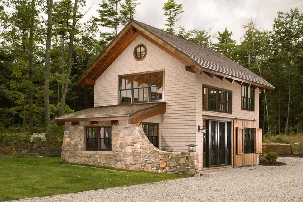 Two-story shingled barn with a curved stone base and round gable window