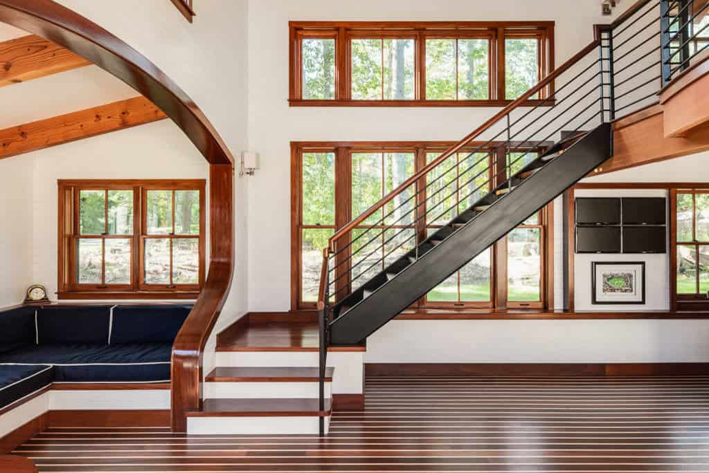 Steel and wood staircase beside an arched window seat and striped teak floor
