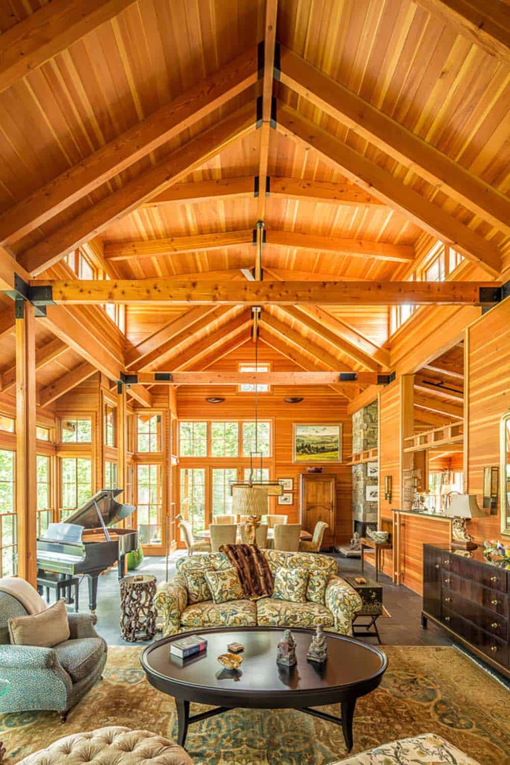 Great room with soaring timber trusses, grand piano, and dining area beyond