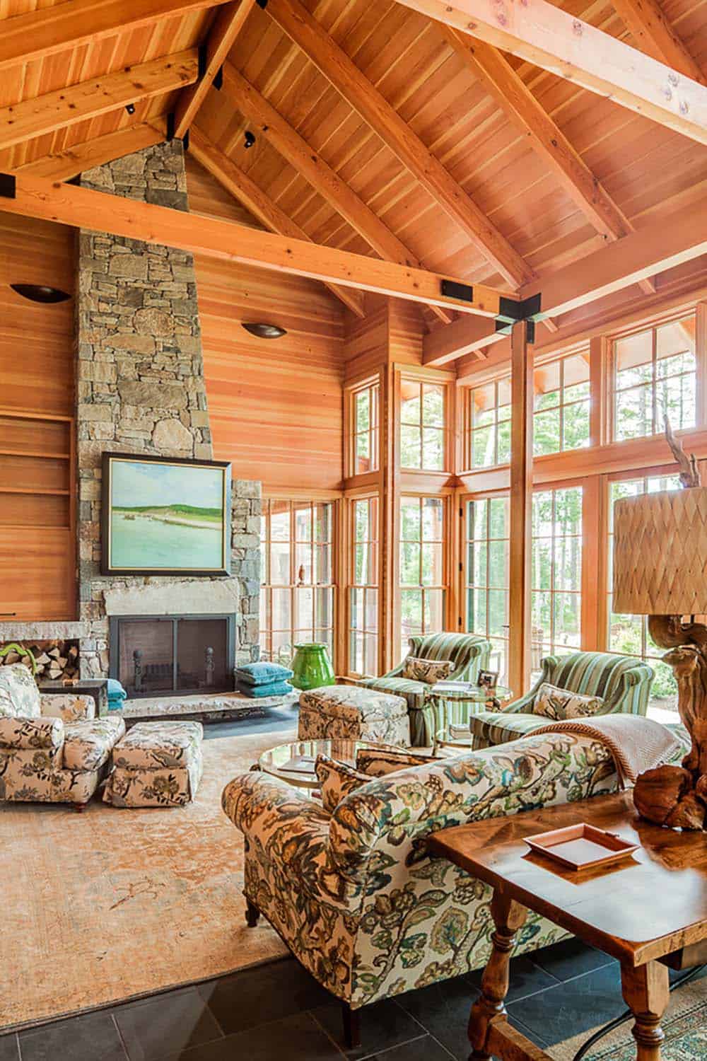 Stone fireplace with coastal painting, wood storage niche, and floral sofa