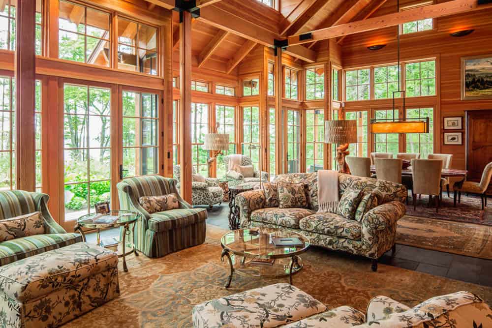 Sitting area surrounded by floor-to-ceiling windows and views of the woods