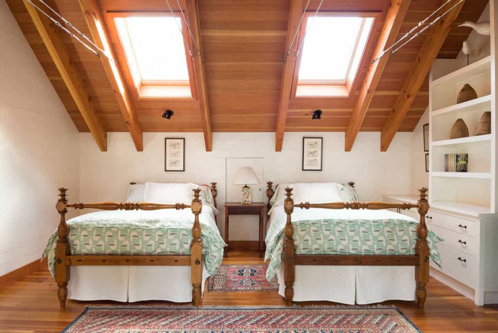 Attic guest room with twin beds, skylights, and exposed timber rafters