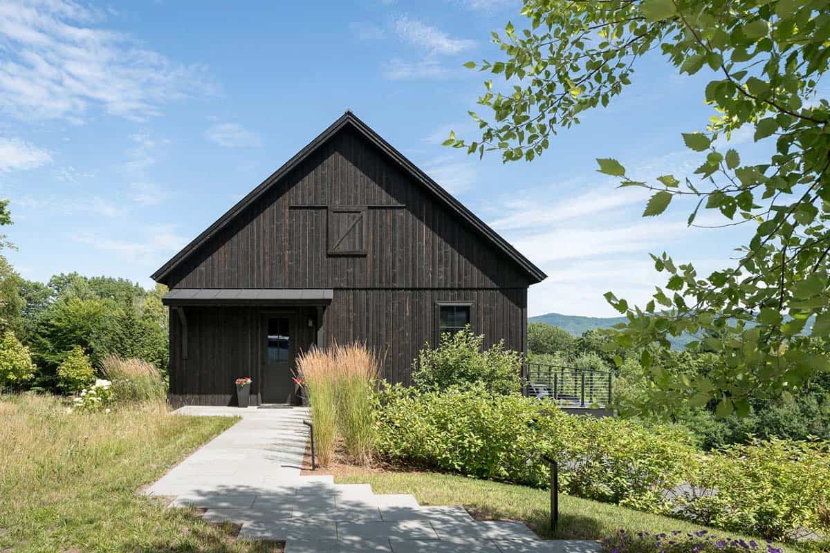 Dark barn-style exterior with gabled roof and stone walkway