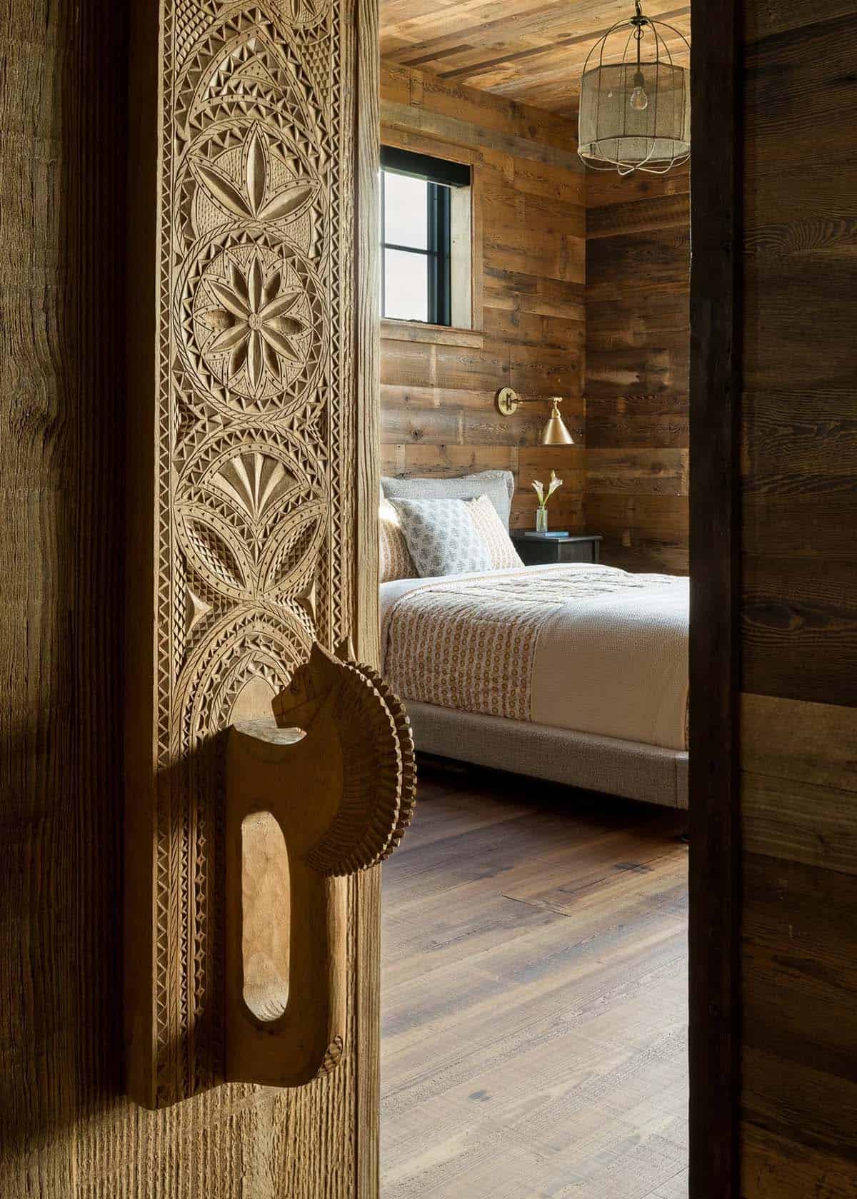 Carved wooden door opening into a rustic bedroom