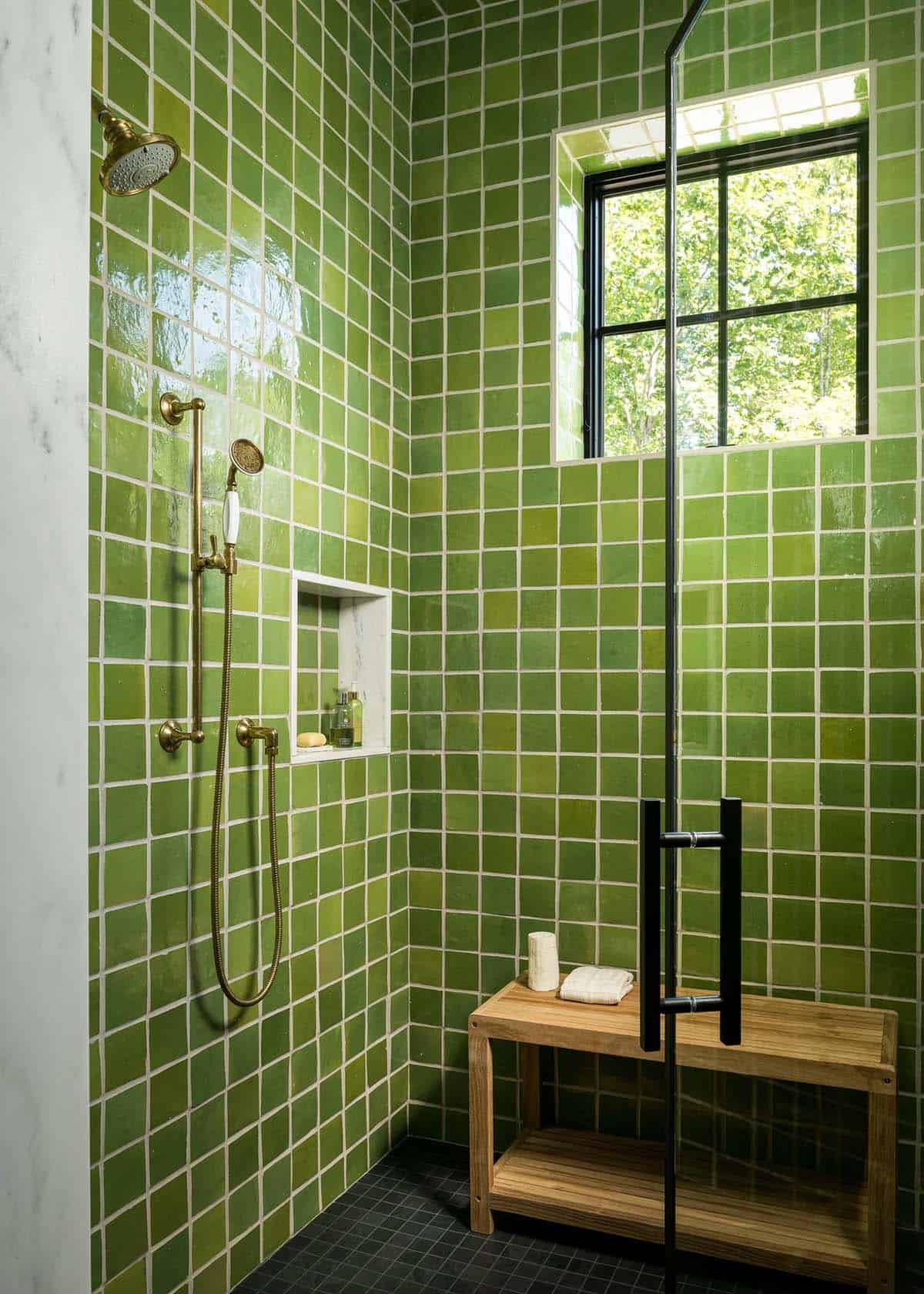 Green tiled shower with brass fixtures and teak bench