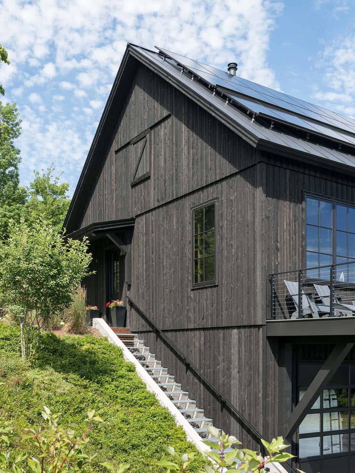 Black barn exterior with solar panel roof and staircase