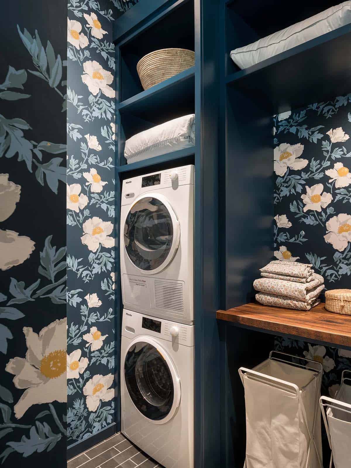 Laundry closet with floral wallpaper and stacked white washer dryer