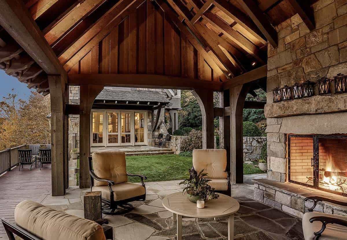 Stone fireplace glowing under covered patio facing the main cottage