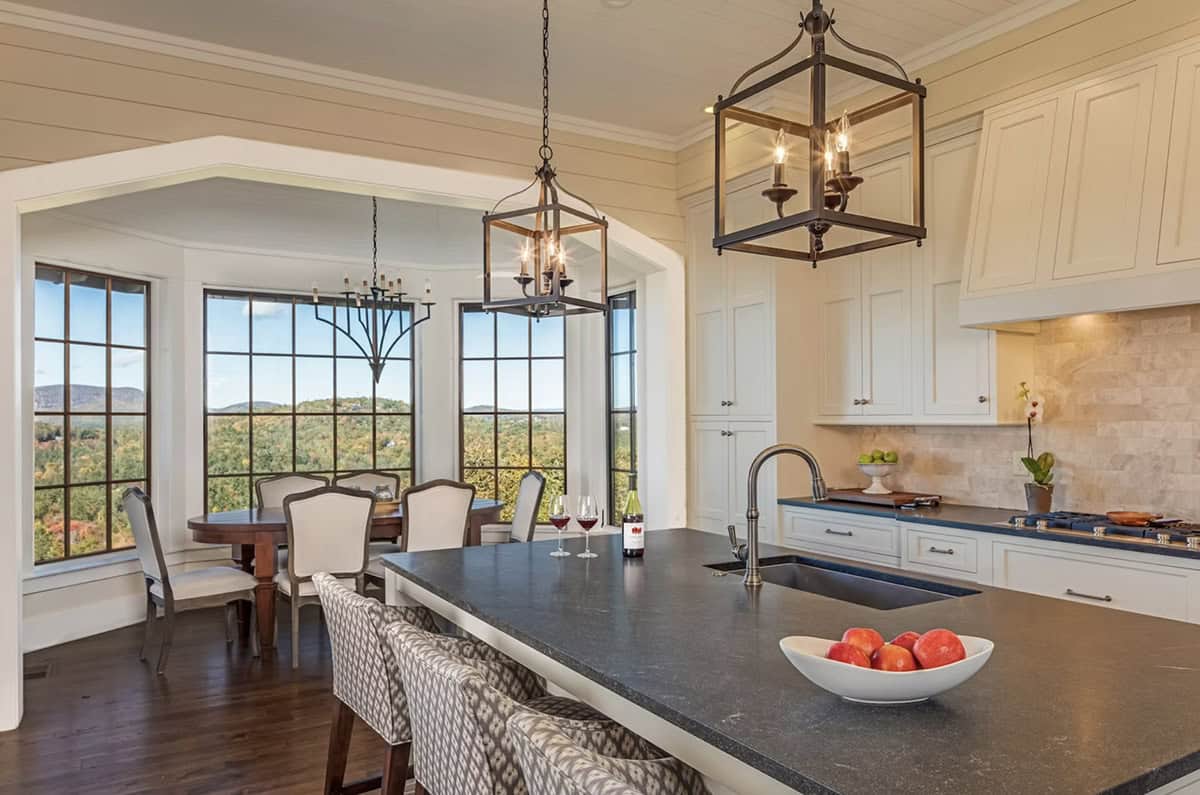 Kitchen island with soapstone counters beside bay-windowed breakfast nook