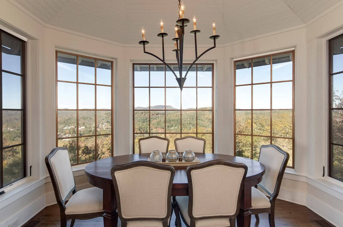 Round dining table surrounded by windows framing sweeping mountain views