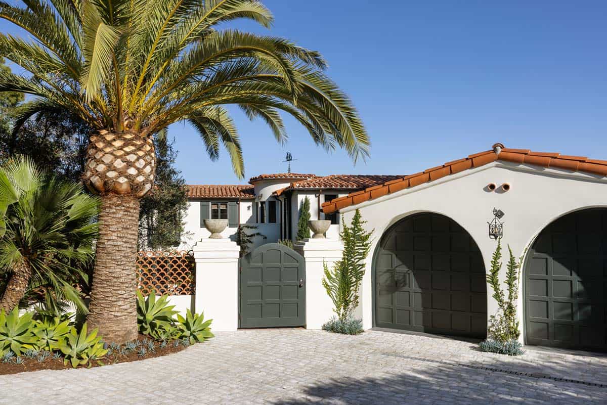 Spanish Colonial Revival exterior with palm tree and arched dark green garage doors