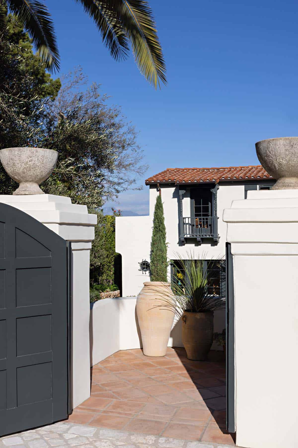 Courtyard entry with terracotta floor, clay urns, and white stucco walls