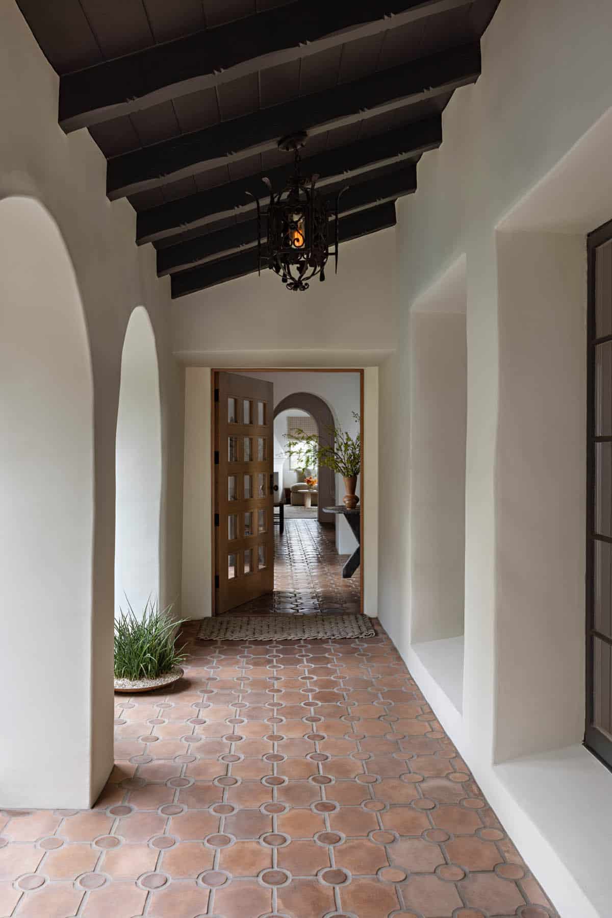 Arched covered walkway with terracotta tile floor and dark wood beam ceiling