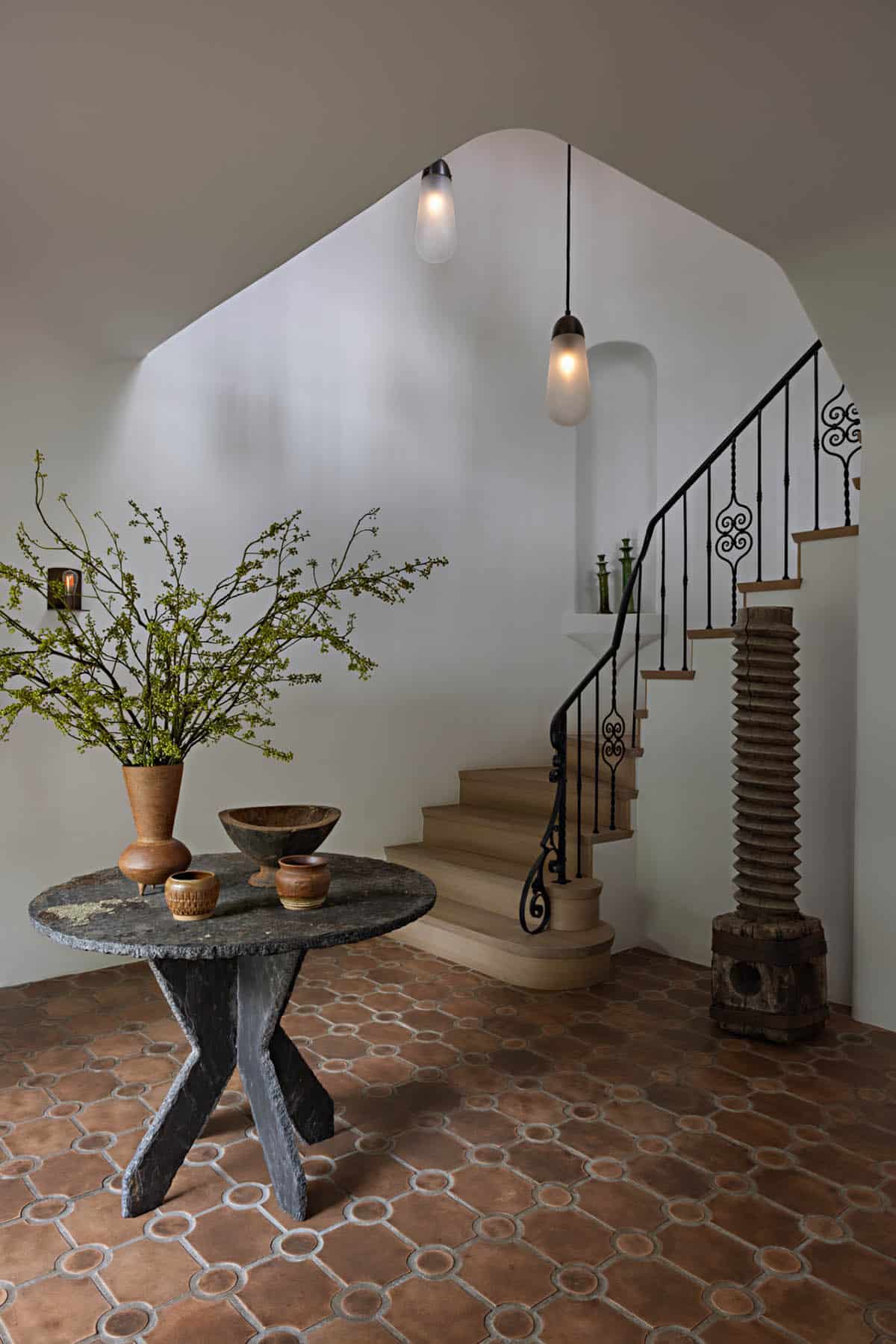 Entry foyer with stone table, curved staircase, and wrought iron railing