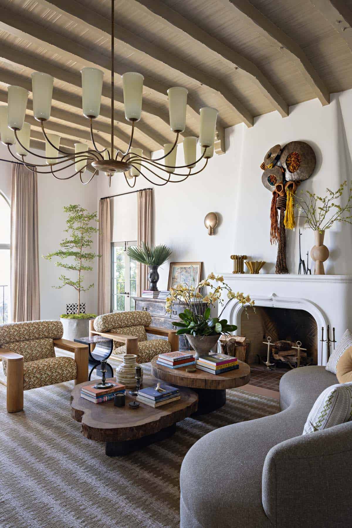 Living room with curved gray sofa, live edge coffee tables, and white fireplace
