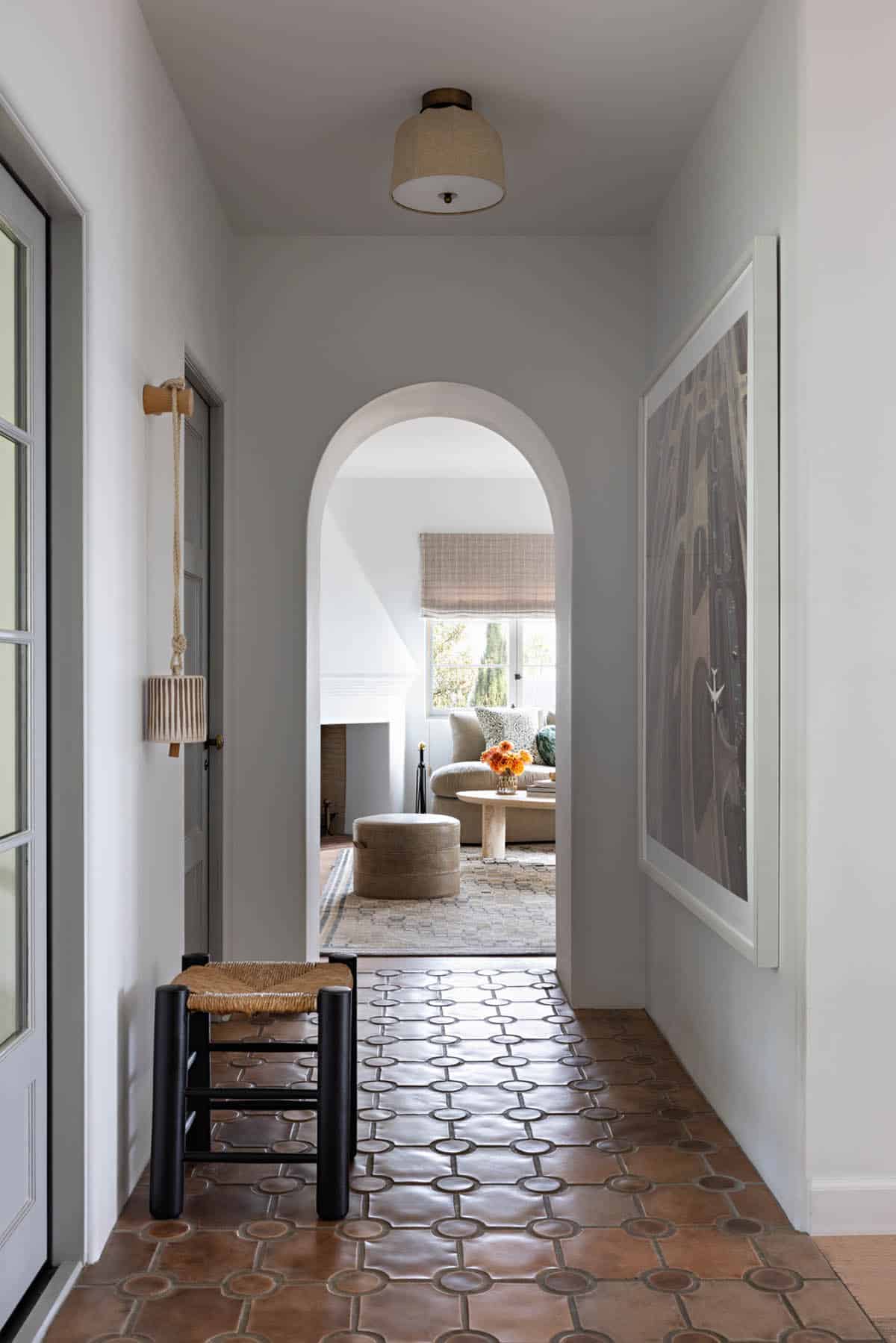 Arched hallway with terracotta tile floor leading to a cozy sitting room