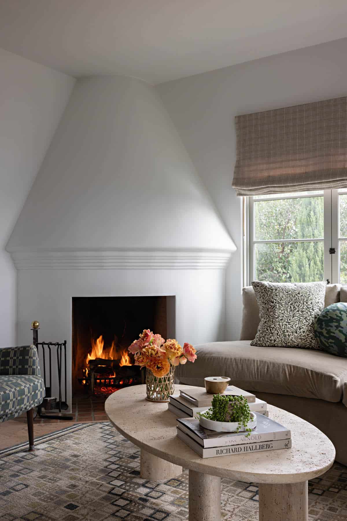 Sitting room corner fireplace with travertine coffee table and plaid roman shade