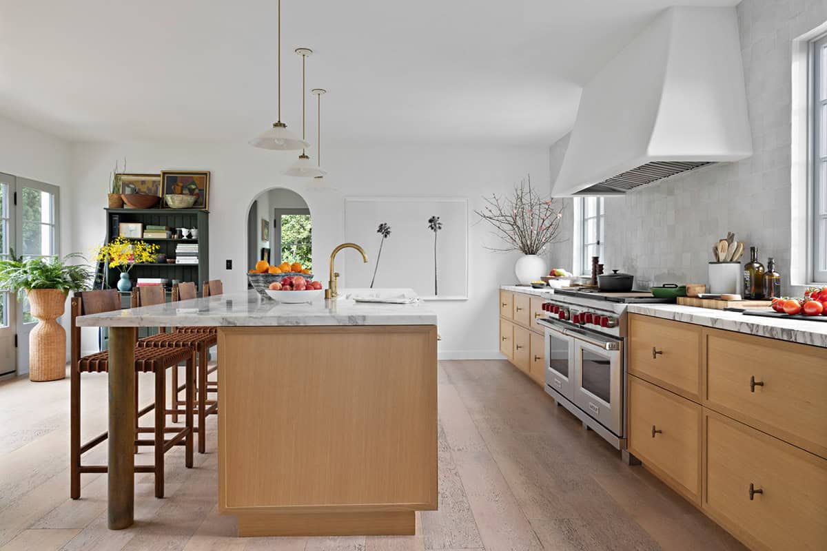 Kitchen with oak island, marble countertop, and white plaster range hood