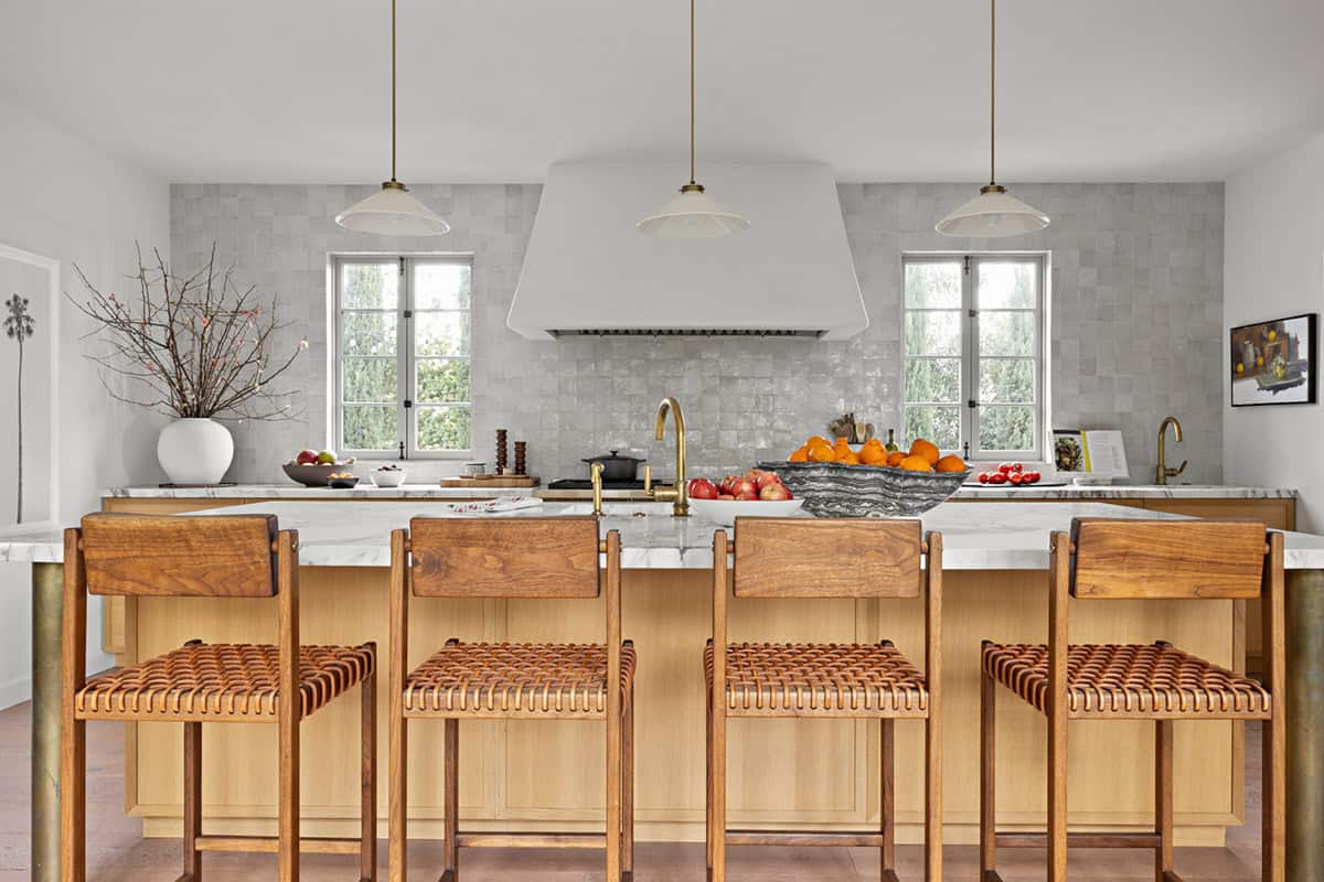Kitchen island with woven leather counter stools and brass faucet