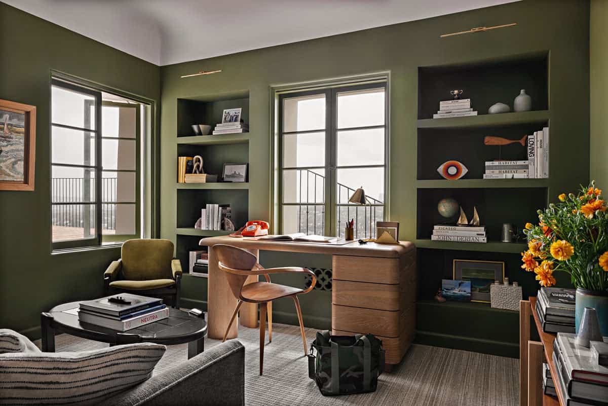 Home office with olive green walls, built-in shelves, and oak desk