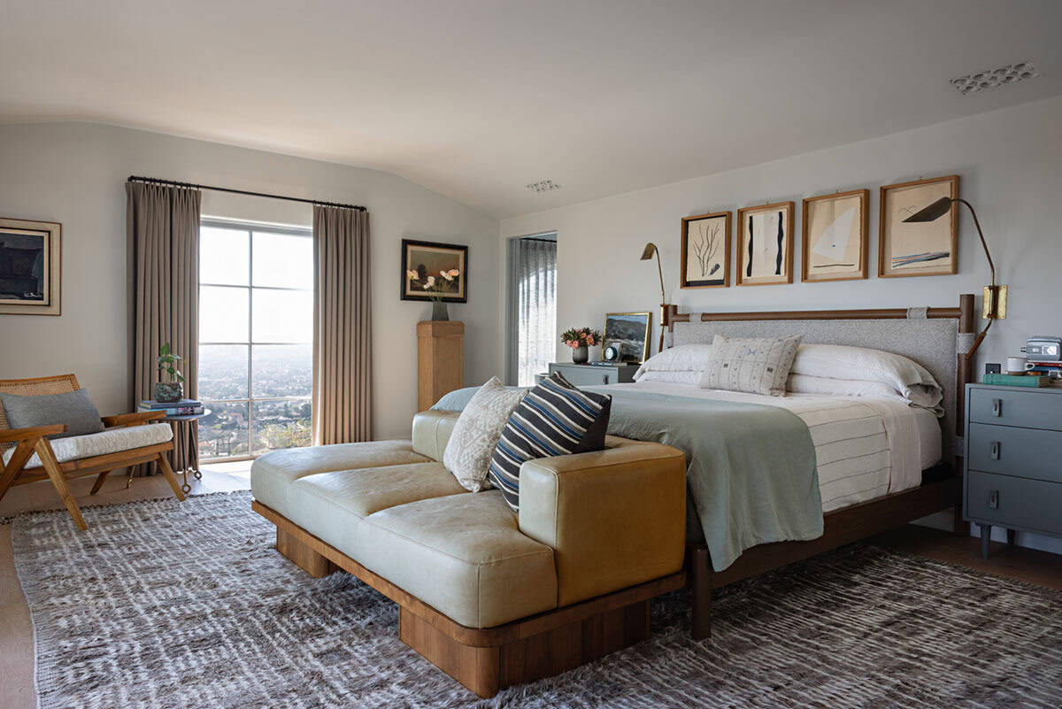 Primary bedroom with leather bench, framed artwork, and hillside city views