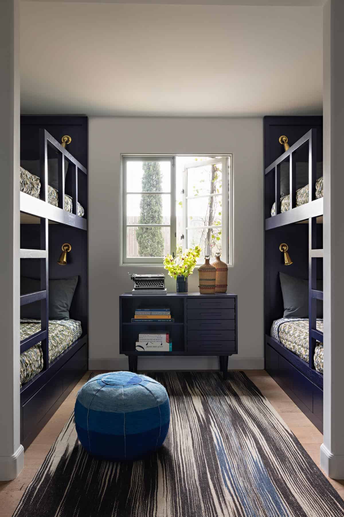 Bunk room with navy built-in bunk beds and brass sconces