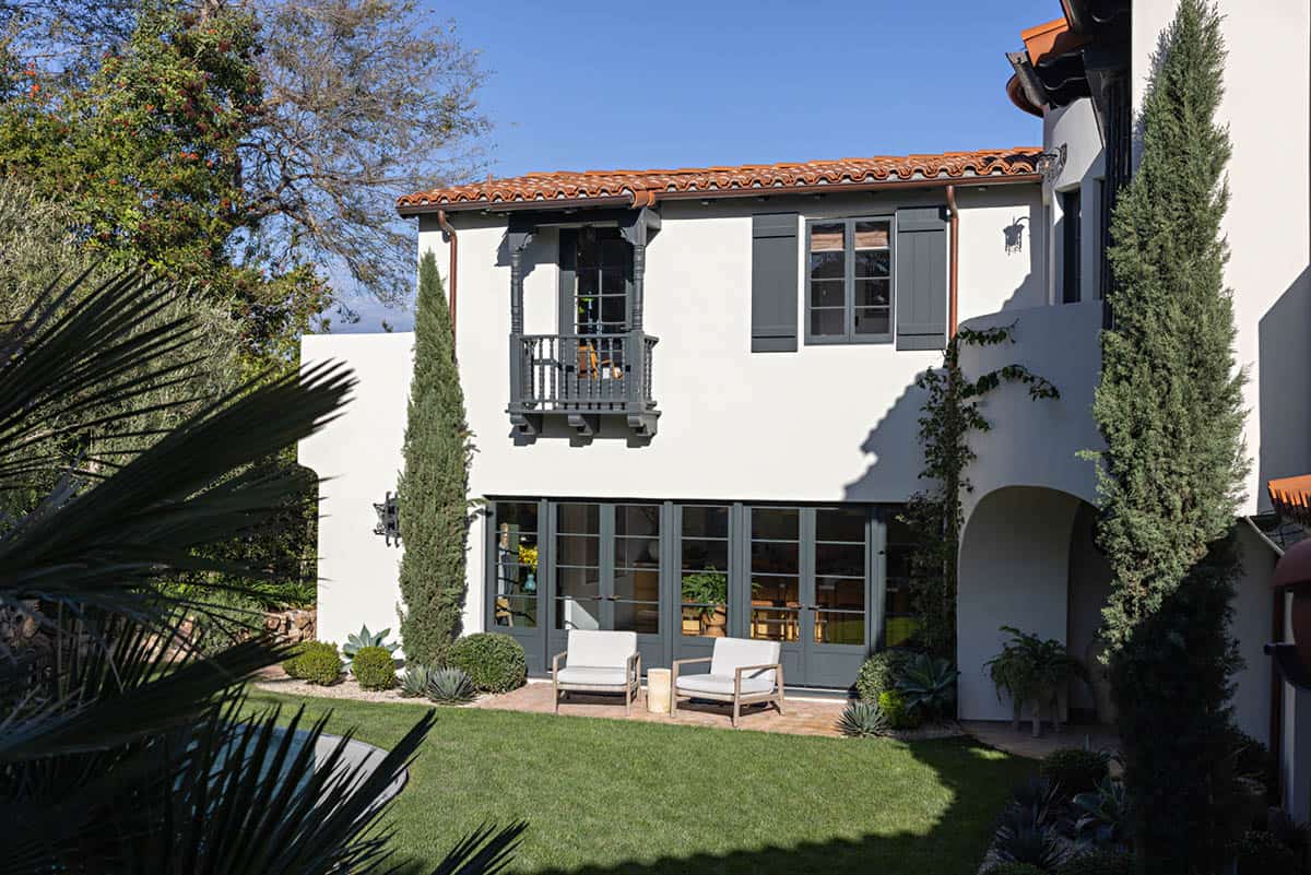Backyard patio with two chairs and a balcony on the stucco facade